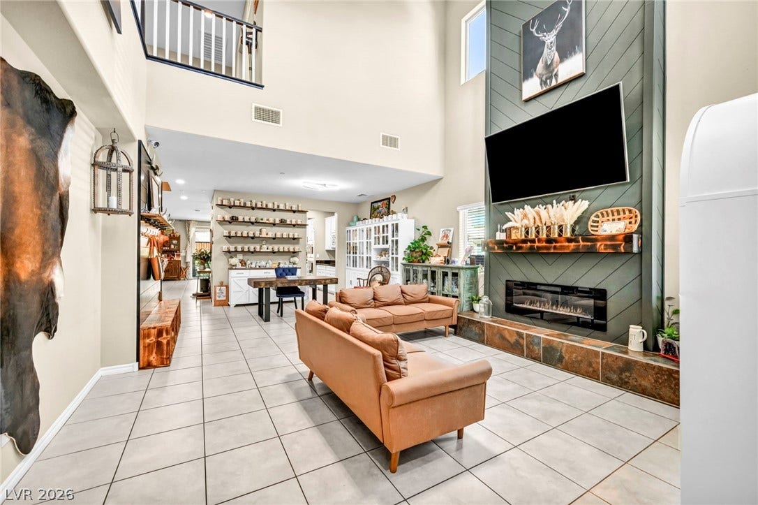 Towering ceilings and a modern fireplace define this open living space anchored by tile flooring.