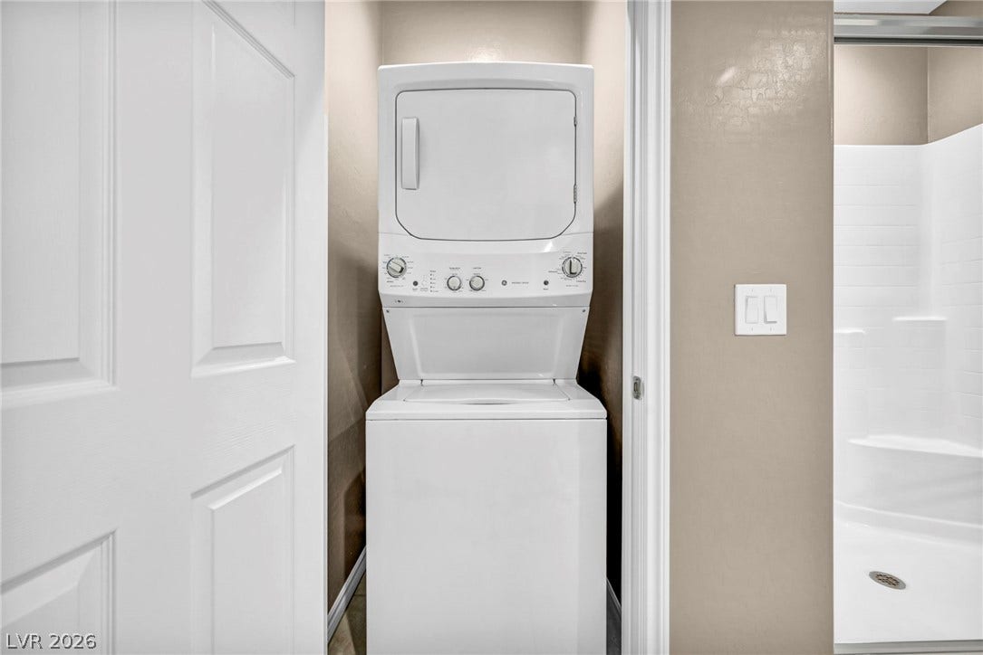 An efficient stacked laundry setup sits adjacent to a clean, modern bathroom.