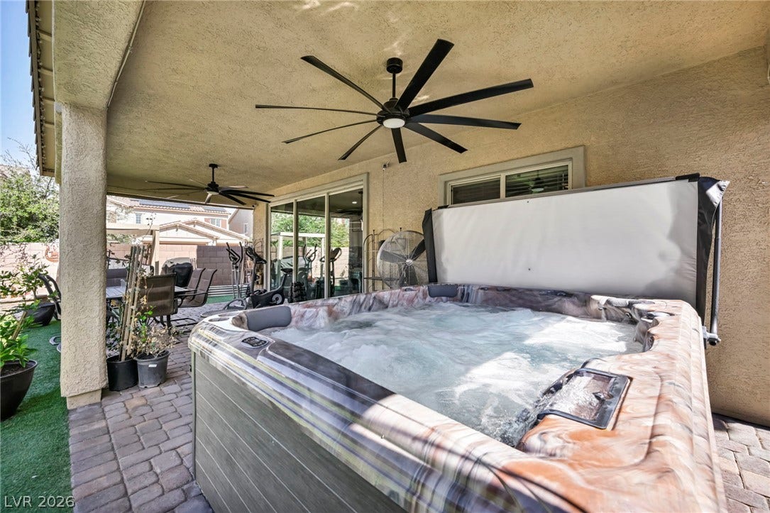 A covered patio with paved flooring shelters an inviting hot tub.