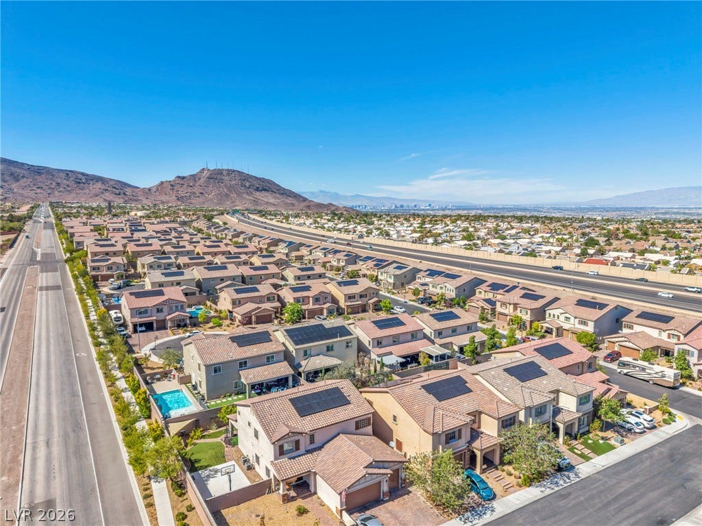 Scenic mountain vistas overlook a quiet residential neighborhood of modern tile-roof homes.