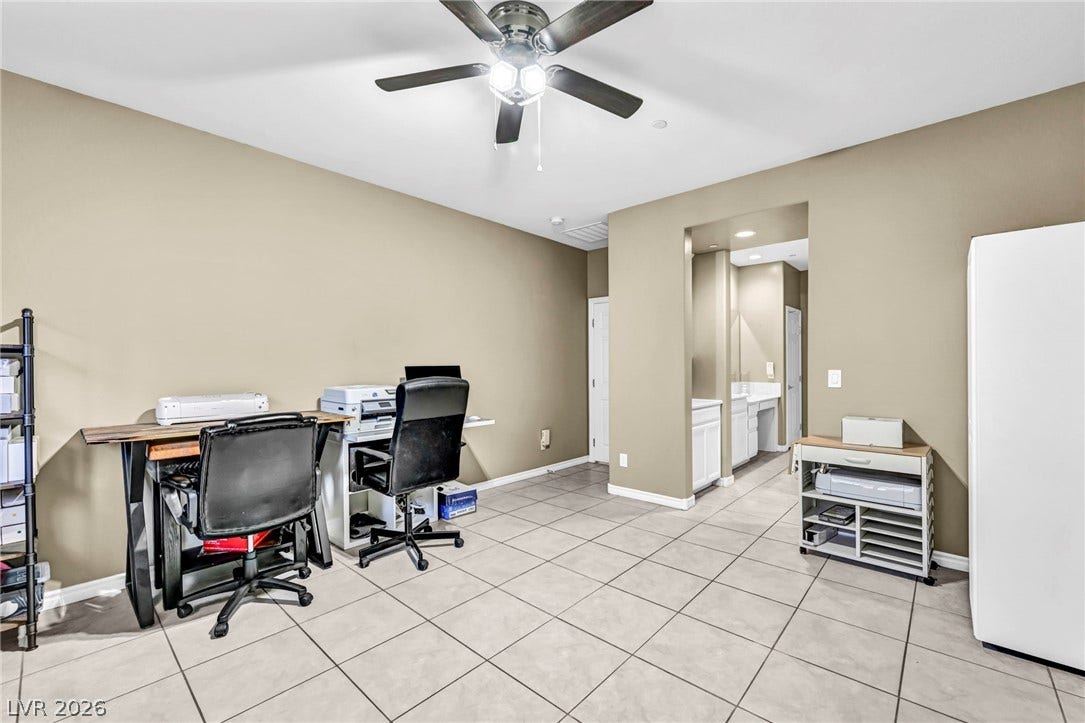 Tiled flooring and neutral walls define this versatile space adjacent to a bathroom hallway.