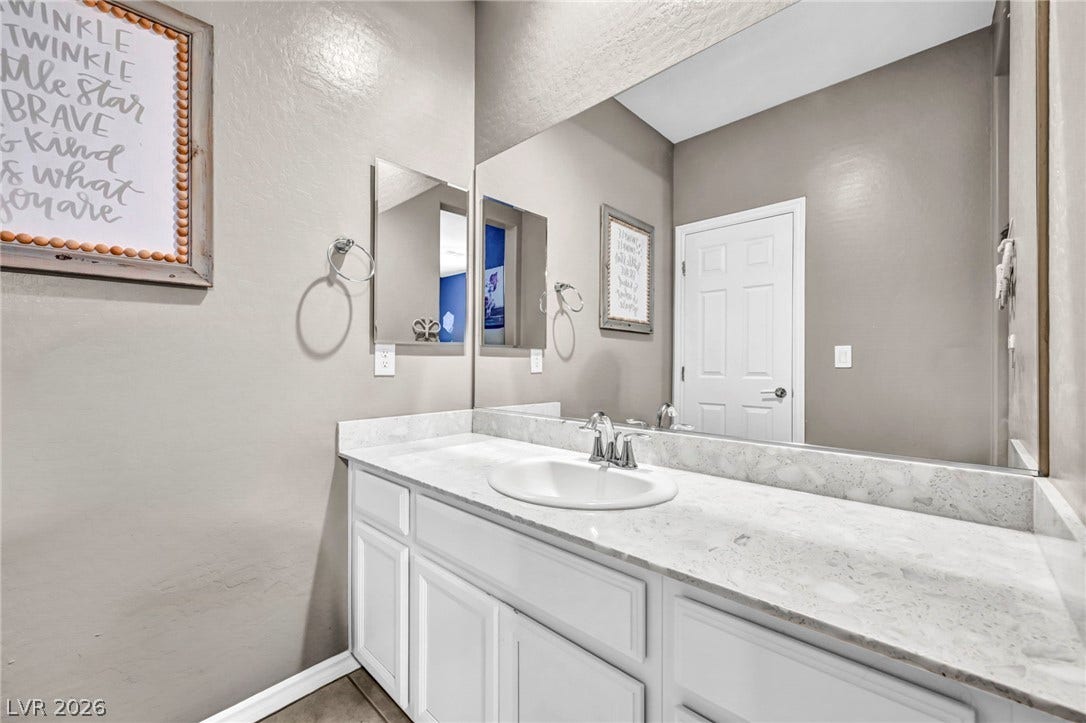 Polished stone countertops pair with white cabinetry in this well-appointed bathroom.