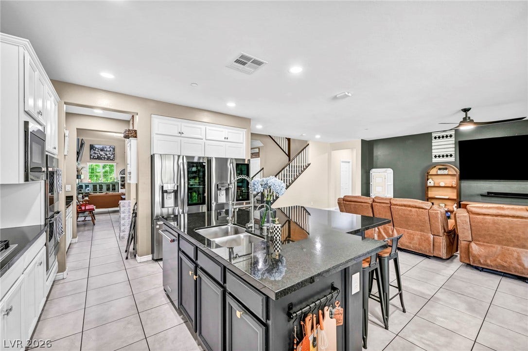 An open kitchen anchors the main floor, featuring a central island and sleek stone countertops.