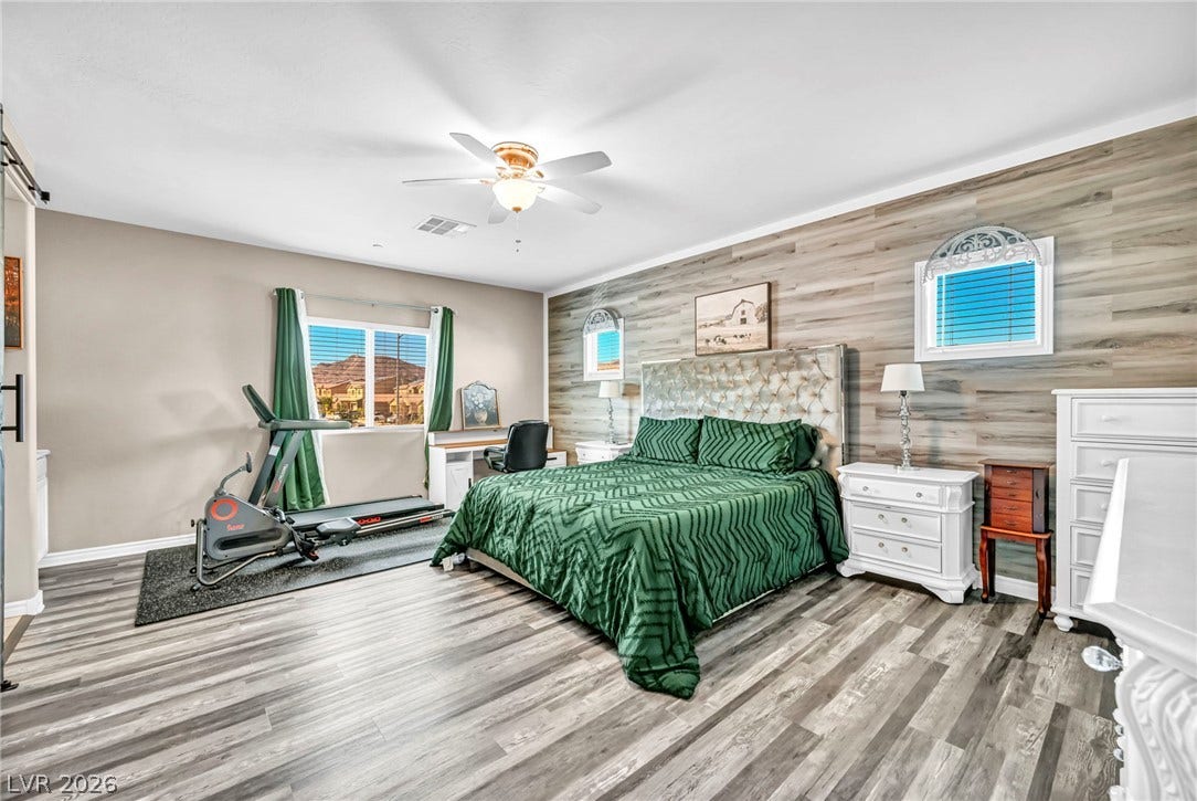 Gleaming wood-look floors pair with a textured wood accent wall in this spacious bedroom.