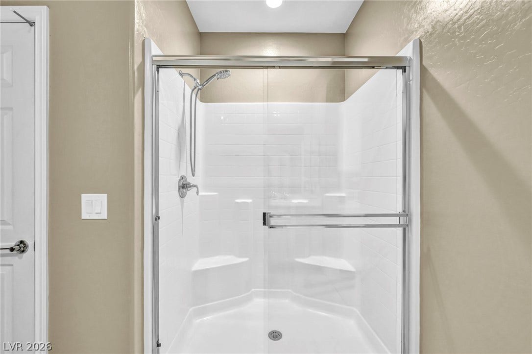 A contemporary walk-in shower features tiled walls and a sliding glass door.