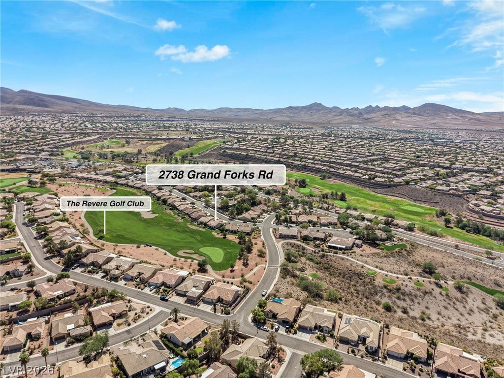 2738 Grand Forks Road, Henderson, NV 89052 An aerial perspective showcases the neighborhood's layout alongside a green golf course and distant mountain ranges.