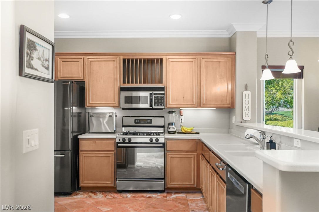 2738 Grand Forks Road, Henderson, NV 89052 Warm wood cabinetry and solid stone countertops anchor this classic, well-lit kitchen space.