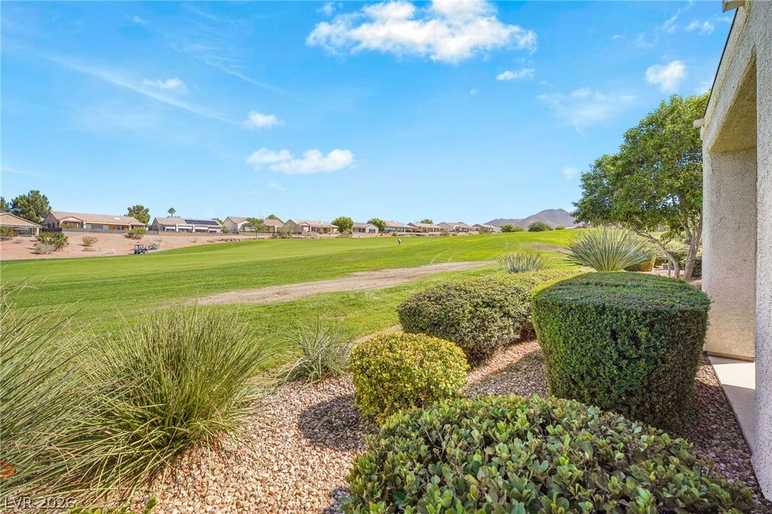 2738 Grand Forks Road, Henderson, NV 89052 Lush manicured hedges frame scenic views of the rolling green golf course under clear skies.