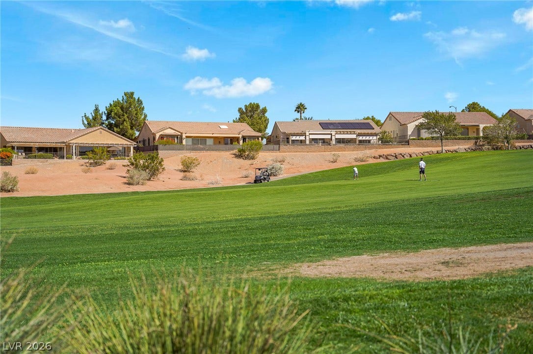 2738 Grand Forks Road, Henderson, NV 89052 Lush fairways stretch out behind single-story neighborhood homes under a blue sky.
