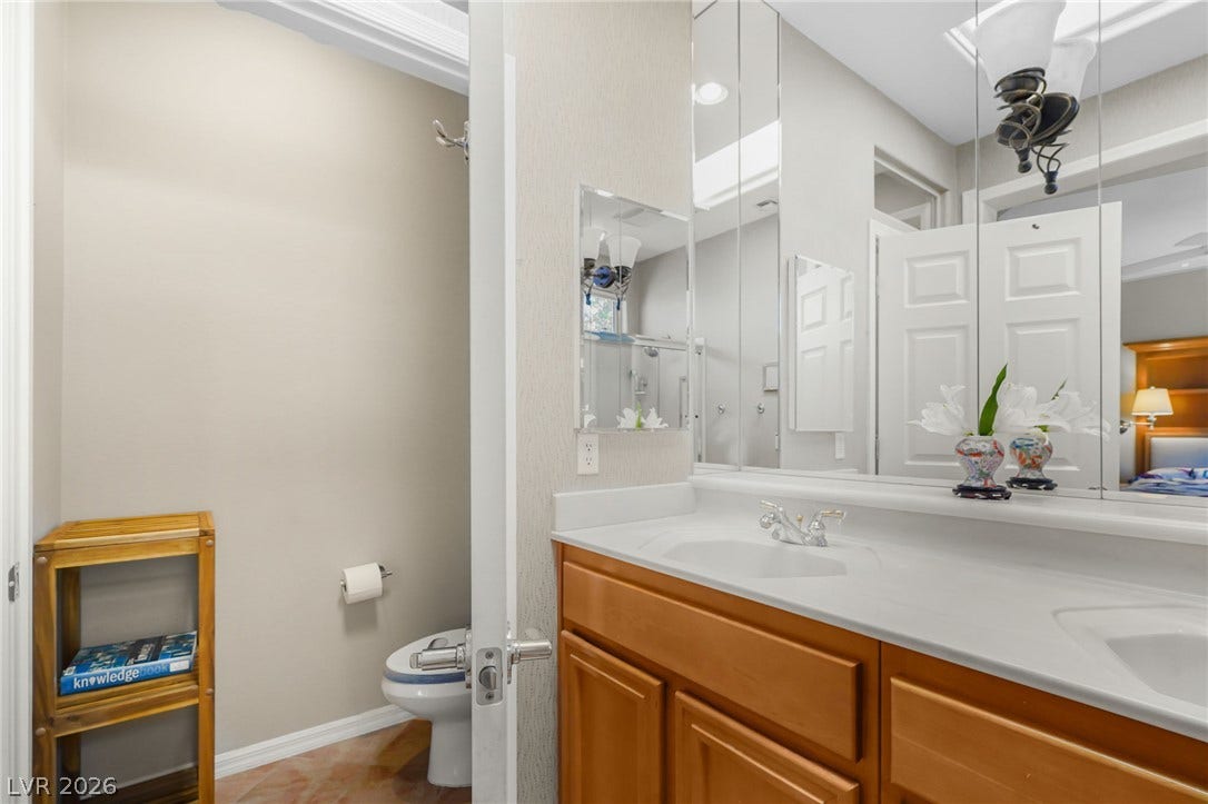 2738 Grand Forks Road, Henderson, NV 89052 Double vanities and classic wood cabinetry anchor this functional bath design.