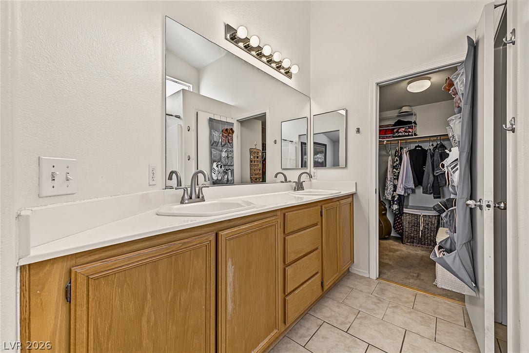 629 Lava Beds Way, North Las Vegas, NV 89084 Double vanity sinks and tile flooring define this bathroom offering direct walk-in closet access.