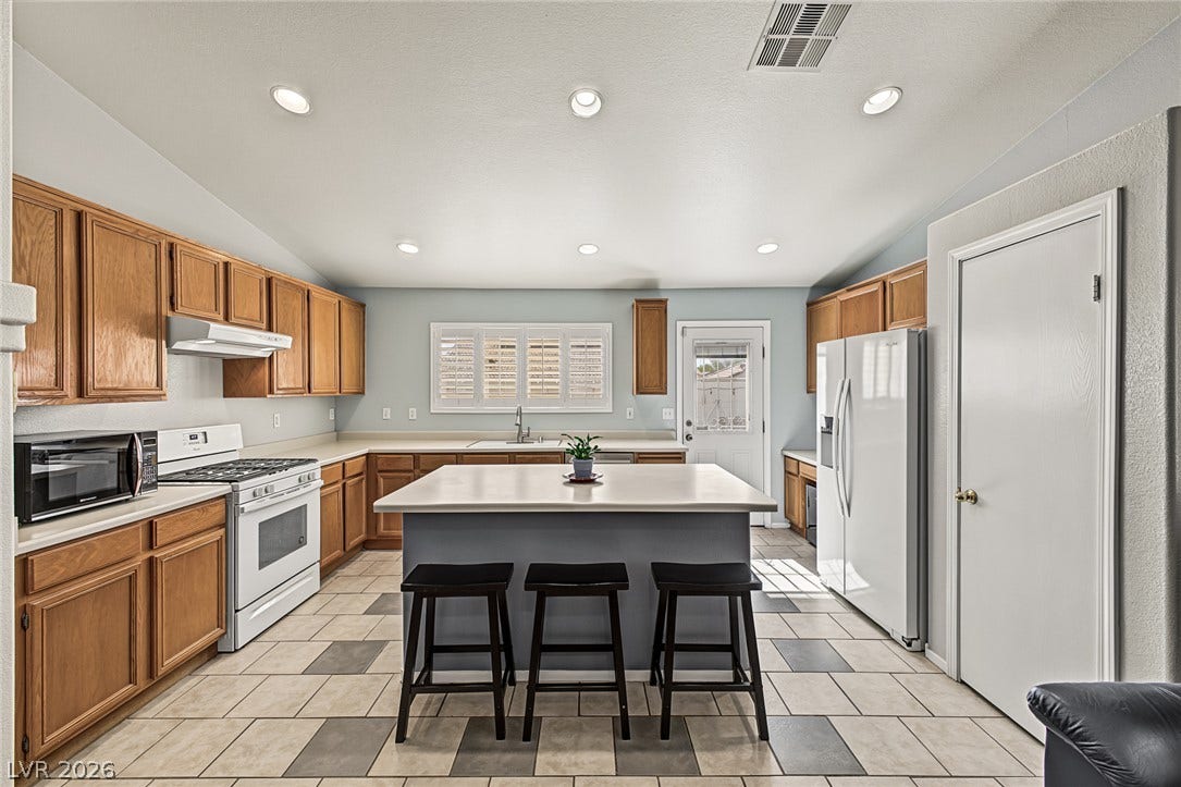 629 Lava Beds Way, North Las Vegas, NV 89084 Ample wooden cabinetry and a central kitchen island define this tile-floored culinary space.