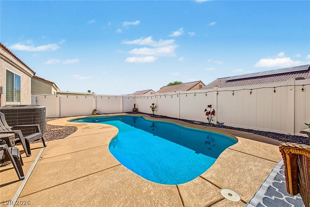 629 Lava Beds Way, North Las Vegas, NV 89084 A private swimming pool is enclosed by a tall perimeter fence under clear blue skies.