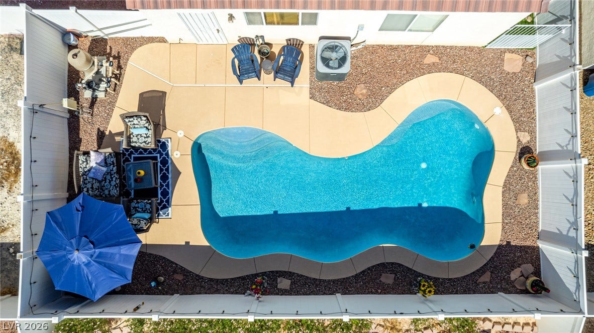 629 Lava Beds Way, North Las Vegas, NV 89084 An aerial perspective showcases a custom-shaped swimming pool framed by concrete decking and privacy fencing.