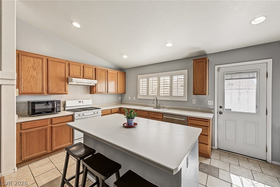 629 Lava Beds Way, North Las Vegas, NV 89084 Ample wooden cabinetry and a central prep island anchor this functional tile-floored kitchen.