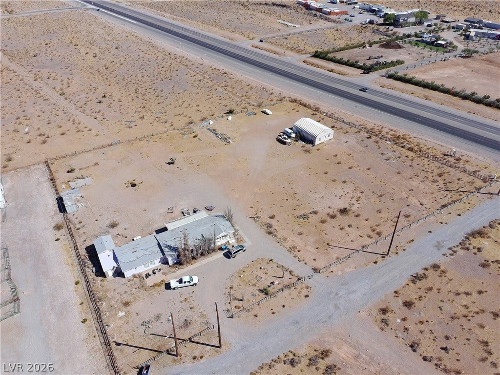12990 State Hwy 160, Las Vegas, NV 89161 An aerial view showcases a spacious desert property bordered by fencing with convenient road access.