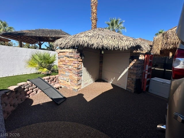 8175 Arville Street, #400, Las Vegas, NV 89139 A thatched-roof structure with stone accents stands adjacent to a paved parking area.