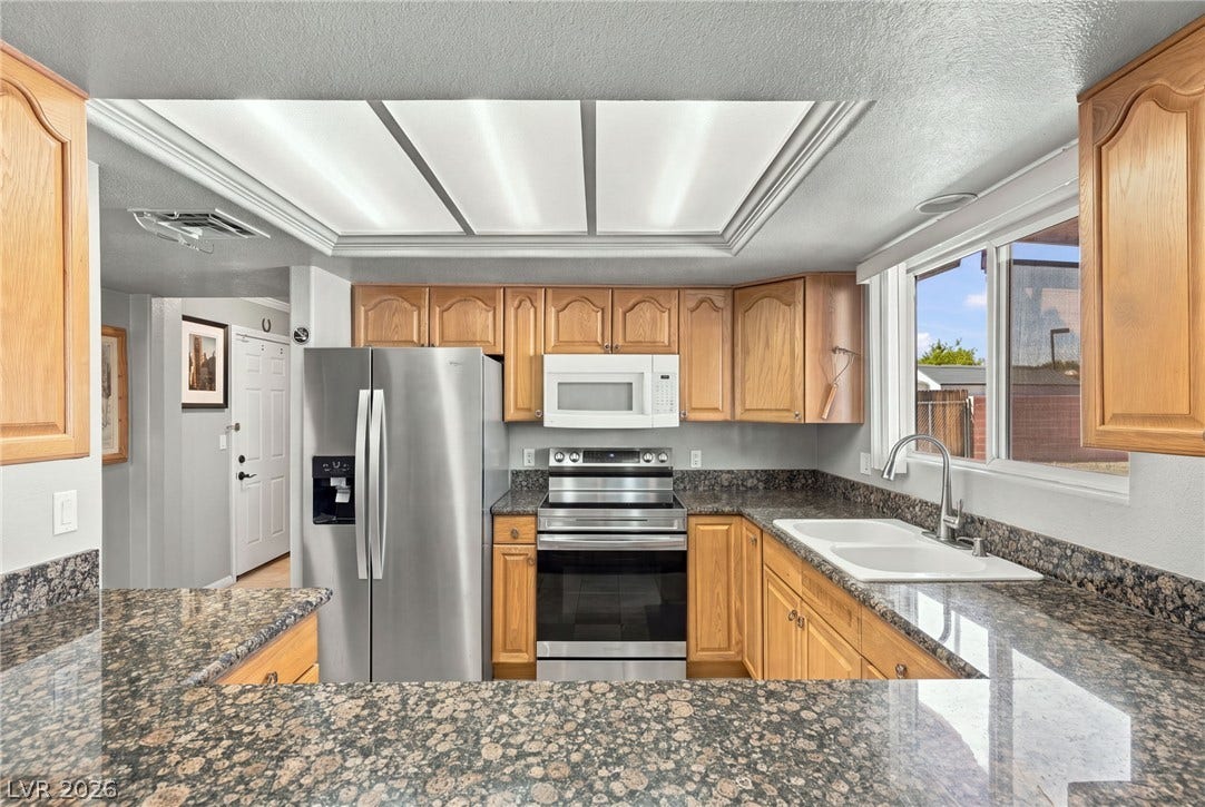 6560 Whispering Sands Drive, Las Vegas, NV 89131 Rich granite countertops pair with classic wood cabinetry and stainless steel appliances in this kitchen.