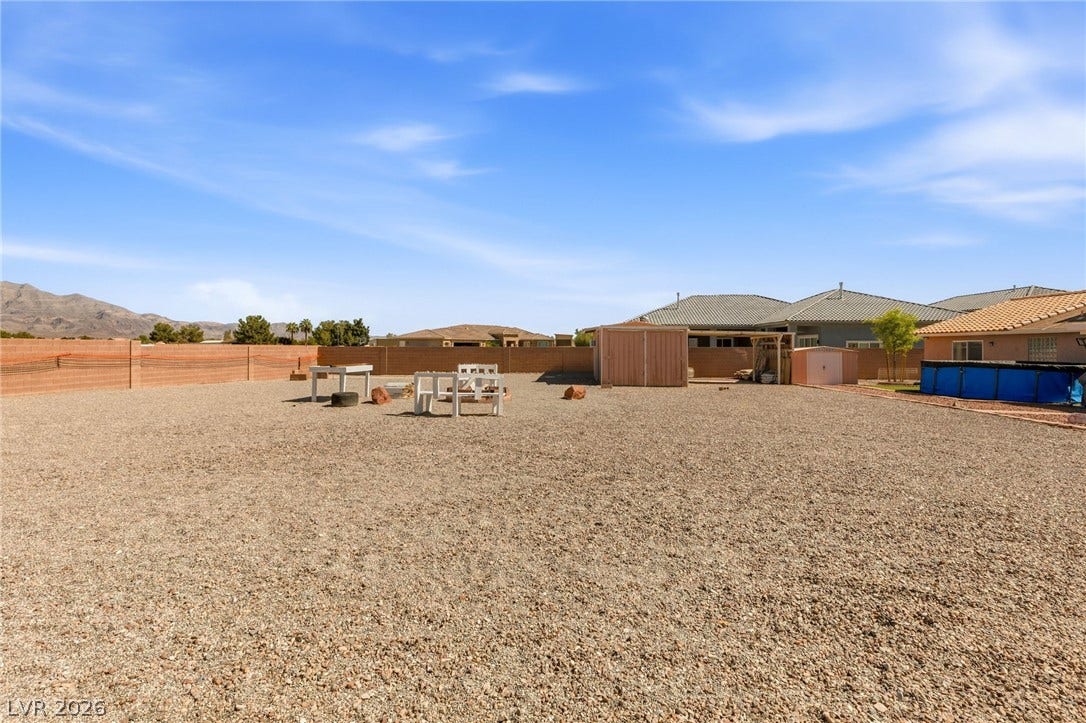 6560 Whispering Sands Drive, Las Vegas, NV 89131 An expansive gravel yard comes fully enclosed by block wall fencing under wide blue skies.