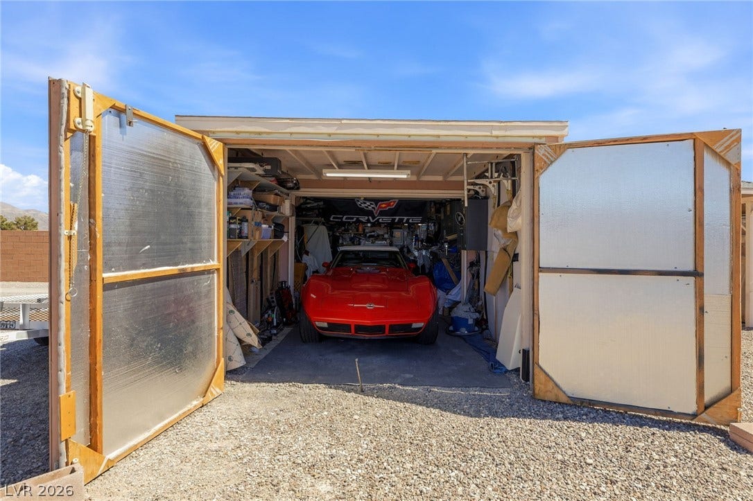 6560 Whispering Sands Drive, Las Vegas, NV 89131 Double doors swing open to reveal a functional workshop and vehicle storage space.