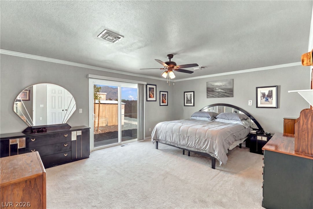 6560 Whispering Sands Drive, Las Vegas, NV 89131 Crown molding and sliding glass doors enhance this well-proportioned bedroom.