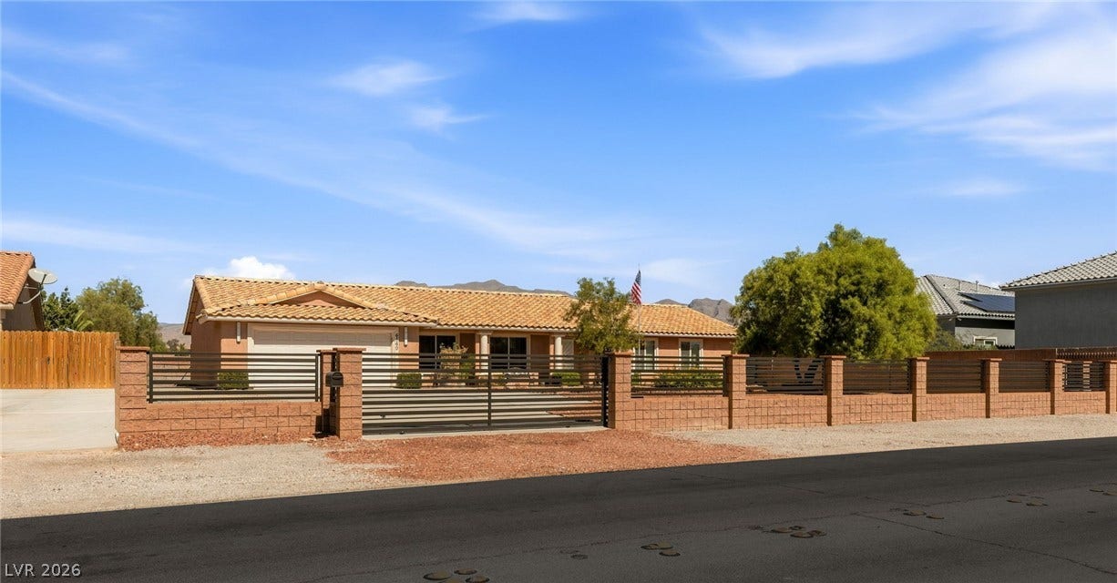 6560 Whispering Sands Drive, Las Vegas, NV 89131 Secure gated entry frames this classic single-story desert home with a tiled roof.