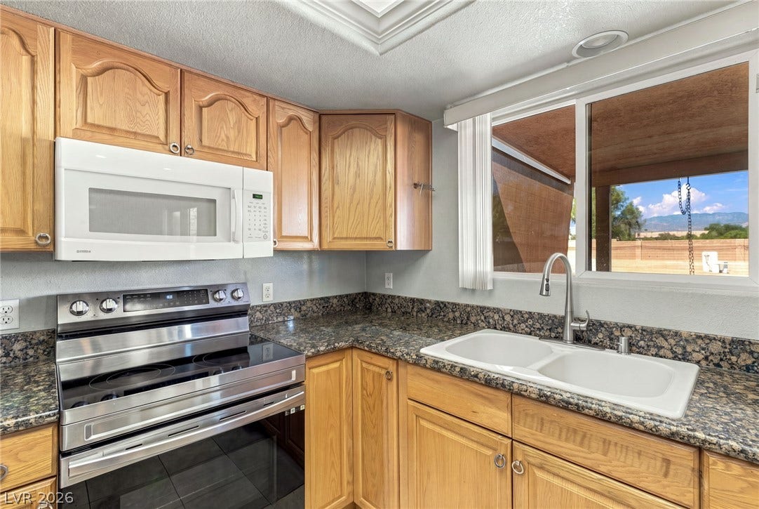 6560 Whispering Sands Drive, Las Vegas, NV 89131 Warm wood cabinetry pairs with stone countertops in this bright, functional kitchen space.