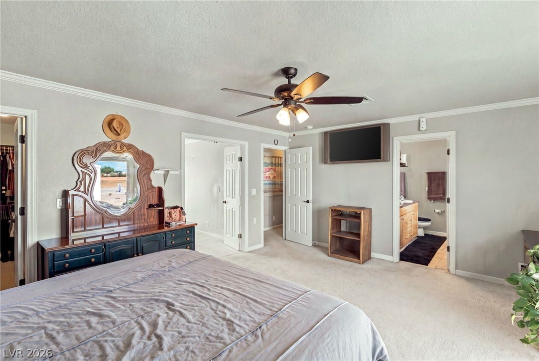 6560 Whispering Sands Drive, Las Vegas, NV 89131 Crown molding frames this comfortable primary suite featuring plush carpeting and an attached bathroom.