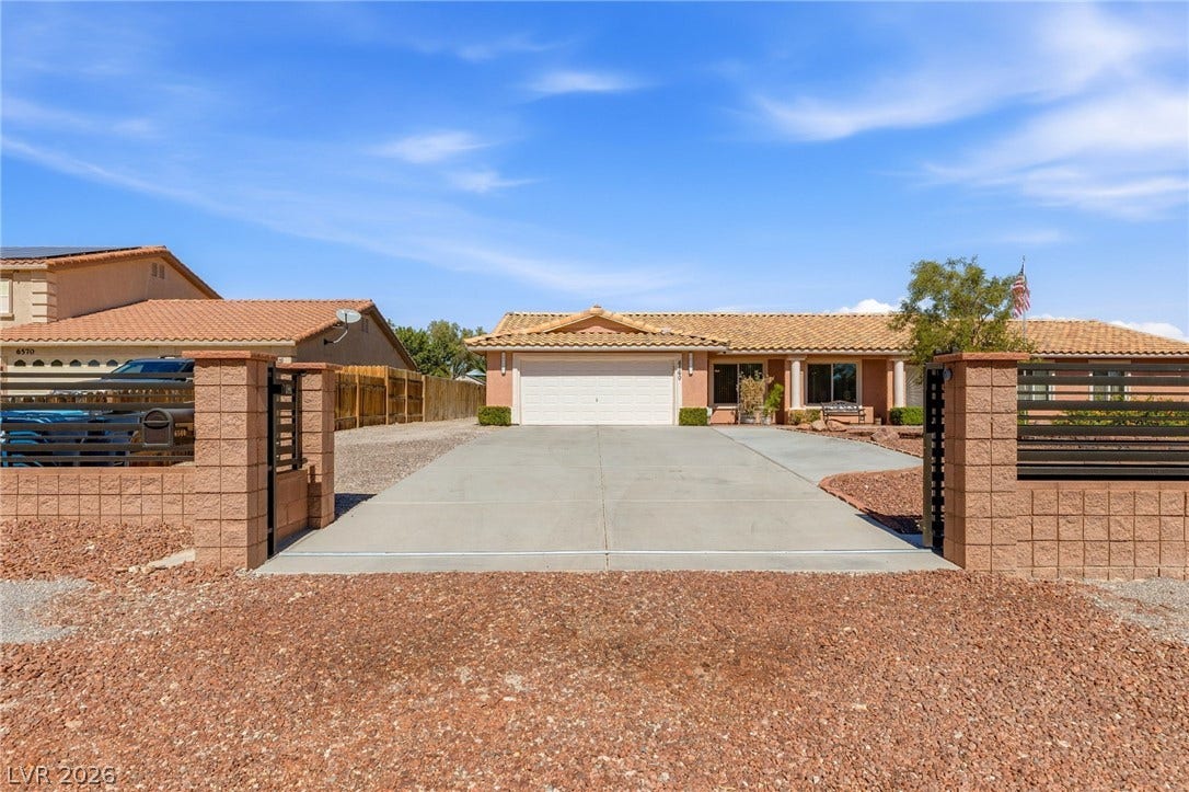6560 Whispering Sands Drive, Las Vegas, NV 89131 A spacious concrete driveway leads past secure gated brick pillars to the two-car garage.