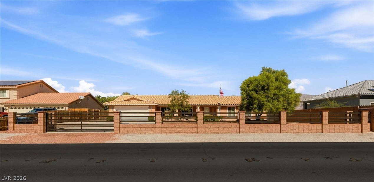 6560 Whispering Sands Drive, Las Vegas, NV 89131 An expansive stucco exterior stands secure behind a custom brick and iron privacy fence.