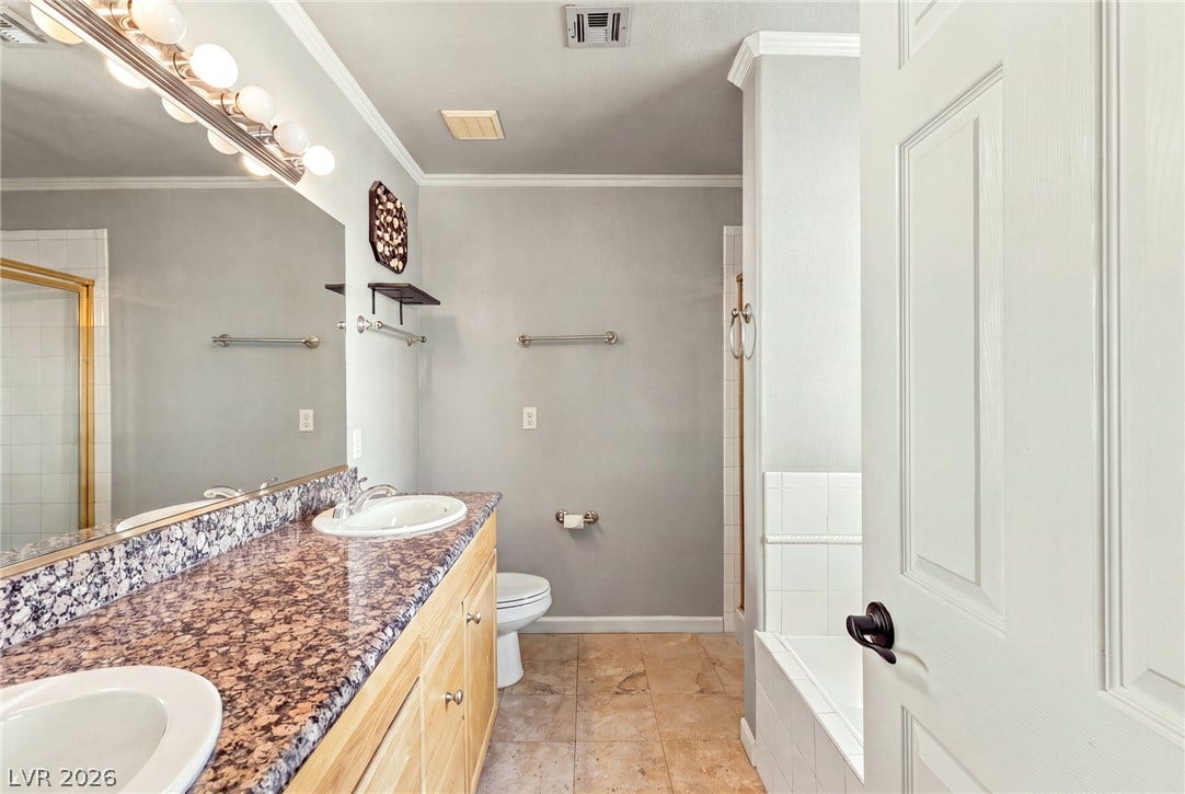 6560 Whispering Sands Drive, Las Vegas, NV 89131 Gleaming stone counters and warm tile floors create an inviting atmosphere in this bathroom.