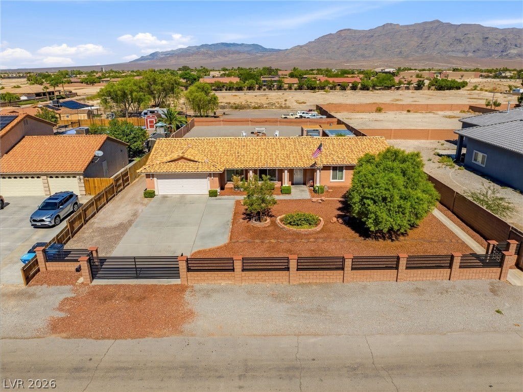 6560 Whispering Sands Drive, Las Vegas, NV 89131 A classic Spanish tile roof crowning this single-level desert home framed by majestic mountain views.