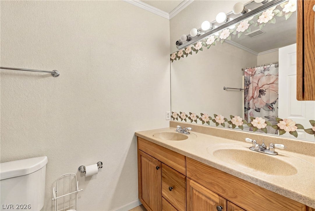 6560 Whispering Sands Drive, Las Vegas, NV 89131 A spacious double vanity and crown molding elevate this functional bathroom design.