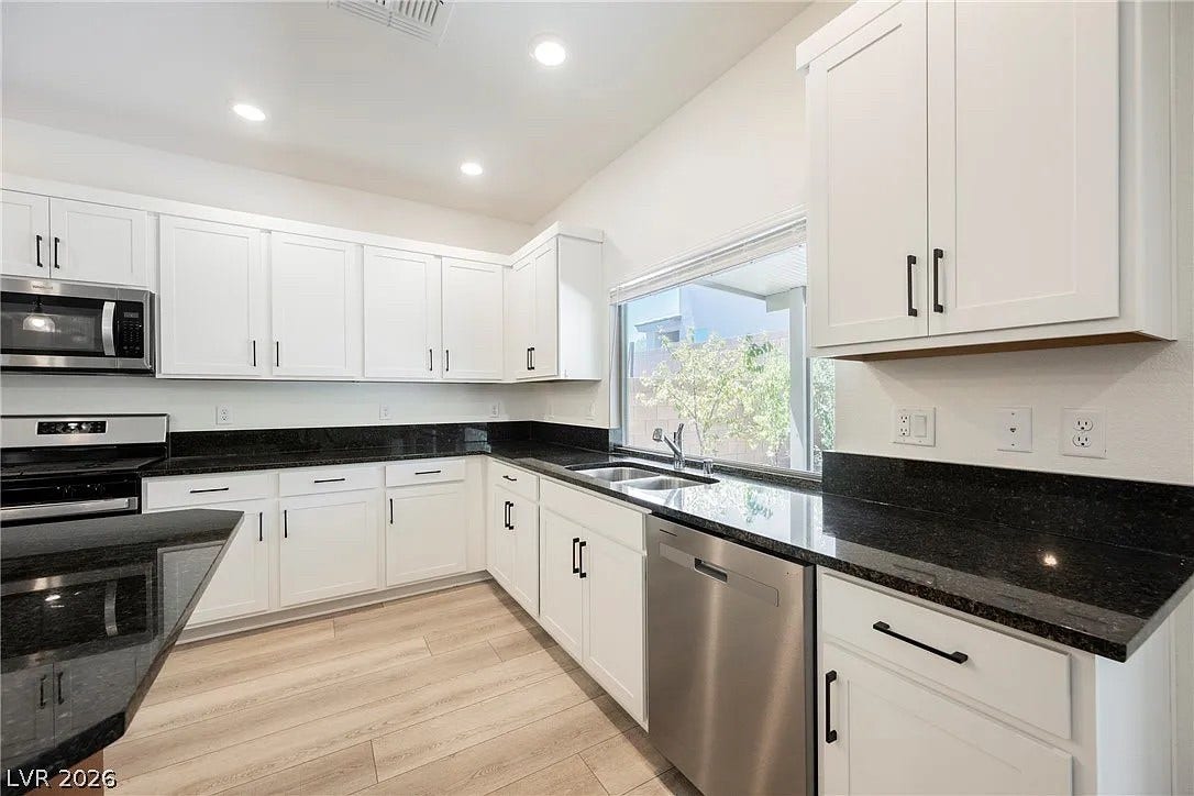 8683 S Black Cordon Road, Las Vegas, NV 89139 Polished granite countertops complement clean white cabinetry and durable wood-look flooring.