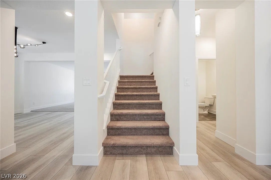 8683 S Black Cordon Road, Las Vegas, NV 89139 Smooth wood-look flooring and carpeted stairs anchor this light-filled modern entryway.