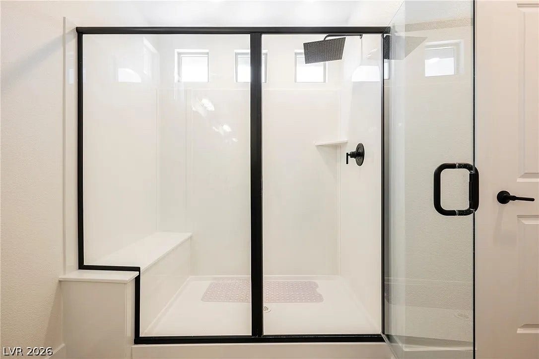 8683 S Black Cordon Road, Las Vegas, NV 89139 Modern black-framed glass panels enclose a sleek walk-in shower featuring a built-in bench.
