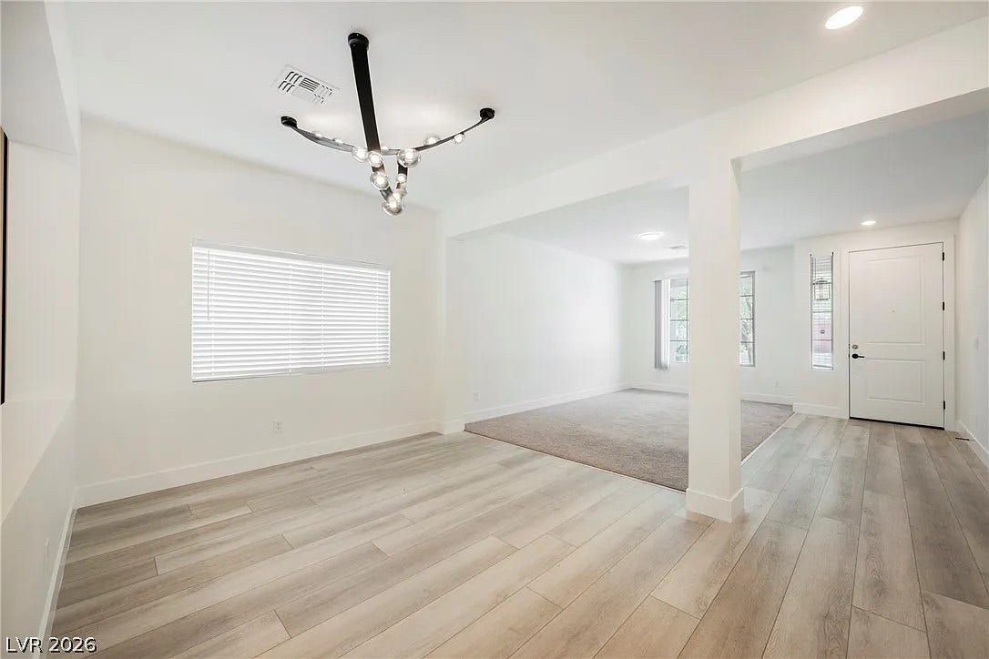 8683 S Black Cordon Road, Las Vegas, NV 89139 Elegant wood-look flooring connects seamlessly to an adjacent carpeted living area.