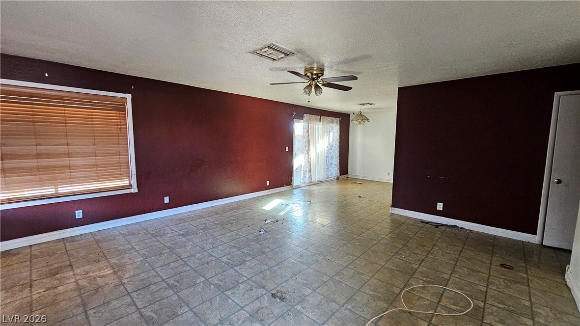 6777 Ledgewood Drive, Las Vegas, NV 89103 Tiled flooring spans this open living space featuring wood-framed windows and sliding glass doors.