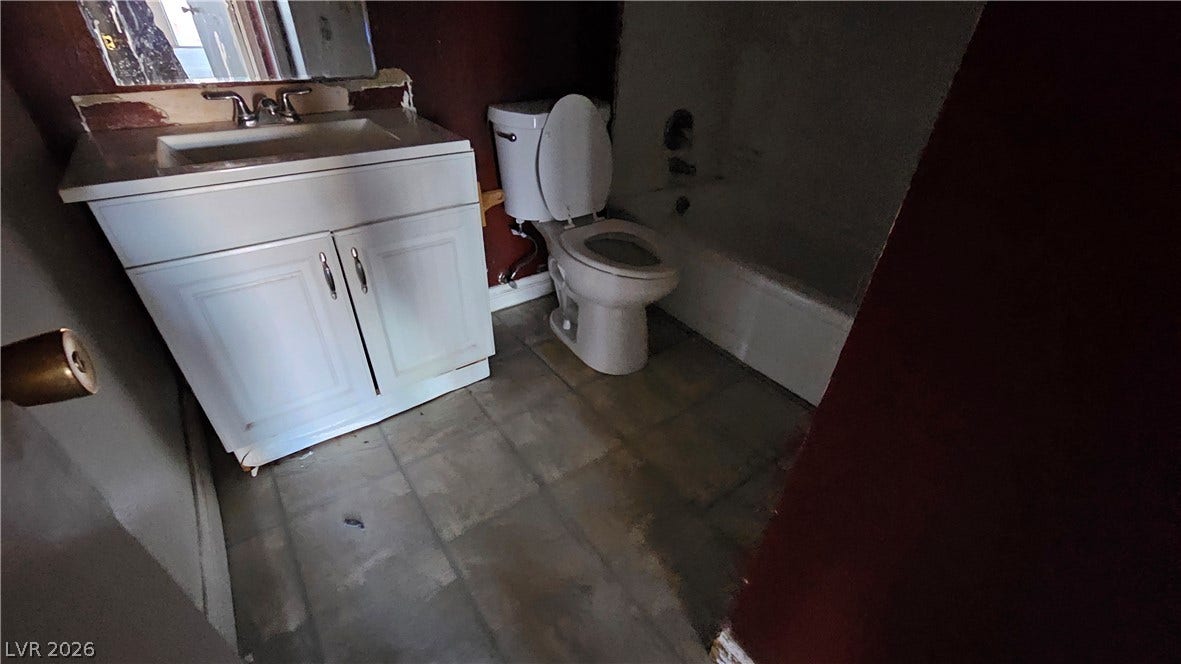 6777 Ledgewood Drive, Las Vegas, NV 89103 A classic layout bathroom features a single vanity, tiled flooring, and a bathtub.