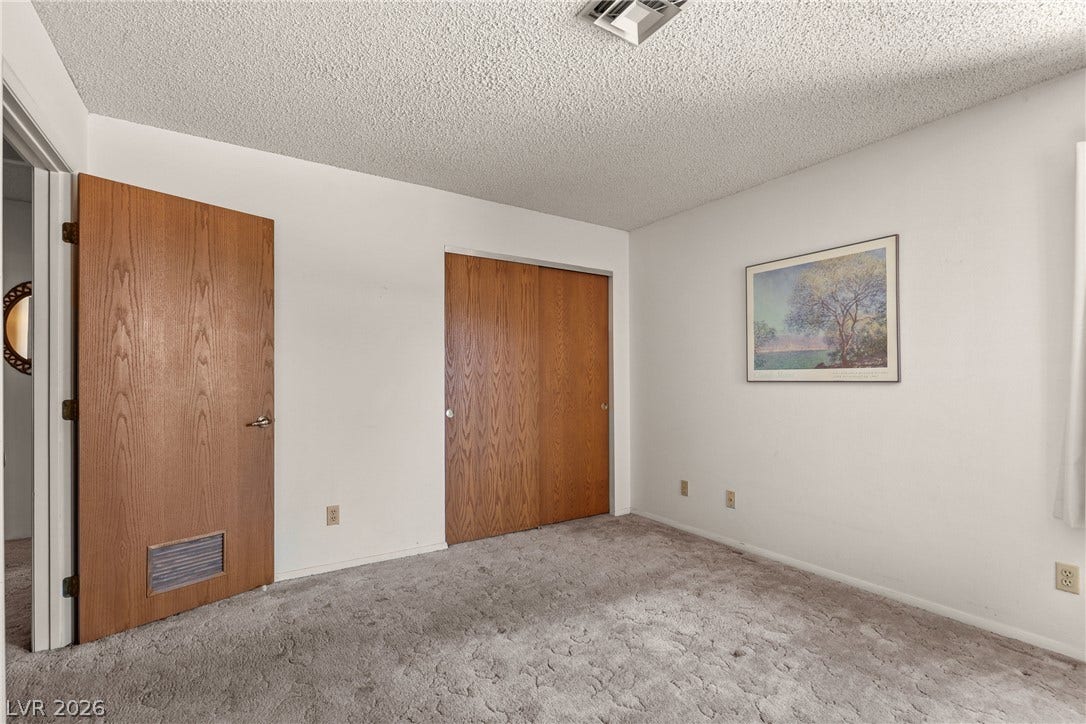 5601 Paseo Recallo Court, Las Vegas, NV 89108 A spacious bedroom features plush carpeting and timeless wood-grain doors.