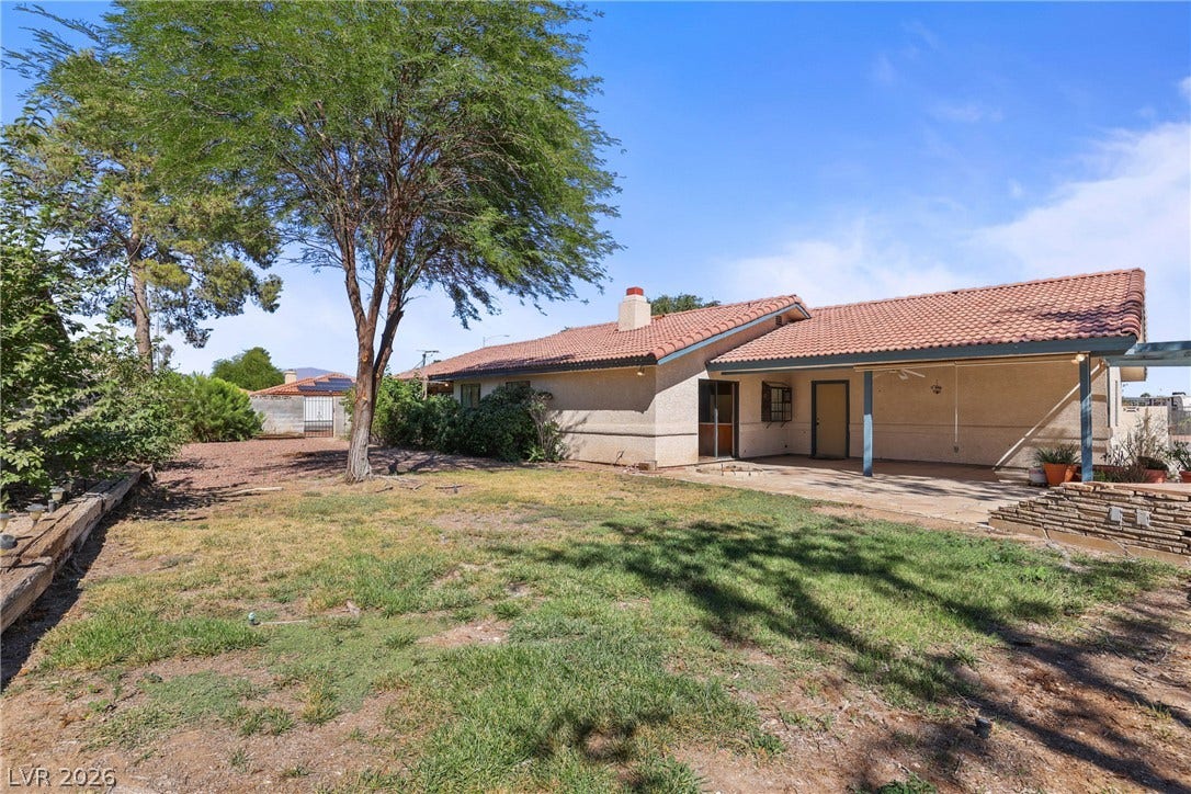 5601 Paseo Recallo Court, Las Vegas, NV 89108 Mature trees shade a spacious backyard with a covered concrete patio and tile roof.
