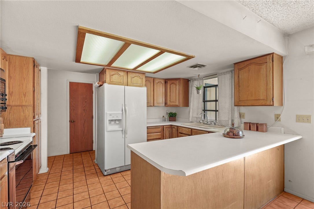 5601 Paseo Recallo Court, Las Vegas, NV 89108 An inviting kitchen features classic wood cabinetry and durable tile flooring.