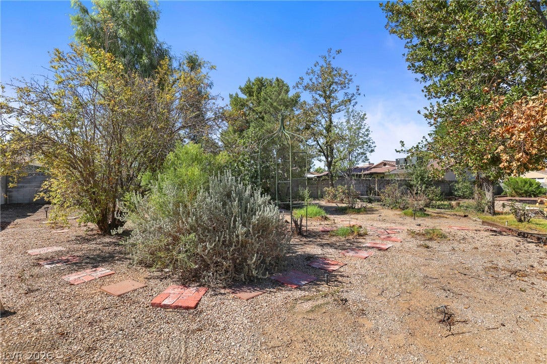5601 Paseo Recallo Court, Las Vegas, NV 89108 Mature trees and low-maintenance plantings frame a spacious backyard with potential for outdoor living.