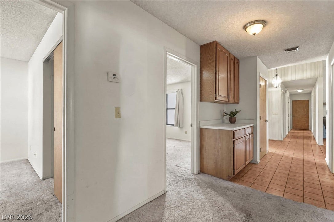 5601 Paseo Recallo Court, Las Vegas, NV 89108 A long tiled hallway adjoins carpeted rooms and built-in wood cabinets.