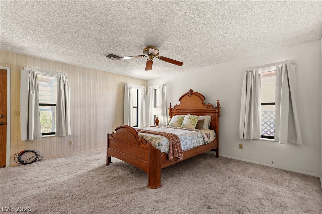 5601 Paseo Recallo Court, Las Vegas, NV 89108 A spacious bedroom features neutral carpeting, abundant natural light, and classic textured walls.