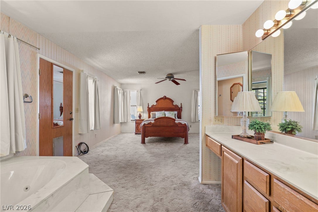 5601 Paseo Recallo Court, Las Vegas, NV 89108 A spacious primary suite features an integrated vanity and steps leading to a soaking tub.