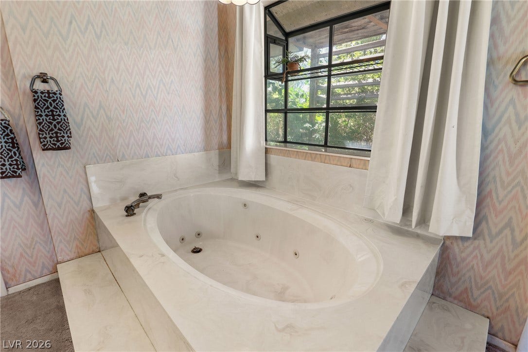 5601 Paseo Recallo Court, Las Vegas, NV 89108 An inviting soaking tub rests below a garden window framing peaceful outdoor greenery views.