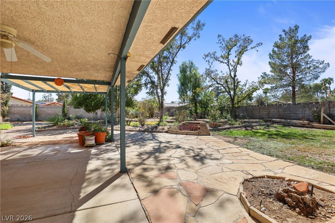5601 Paseo Recallo Court, Las Vegas, NV 89108 Mature trees frame the expansive stone terrace and shaded concrete patio in this peaceful backyard.