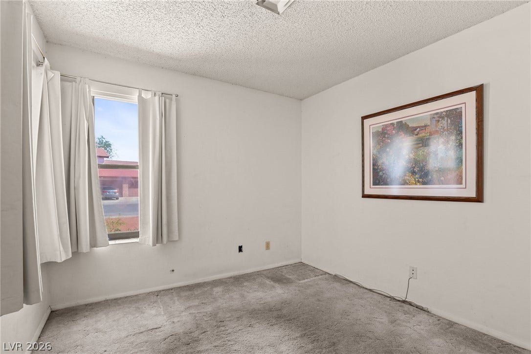 5601 Paseo Recallo Court, Las Vegas, NV 89108 Natural light streams through a large window into this carpeted bedroom space.