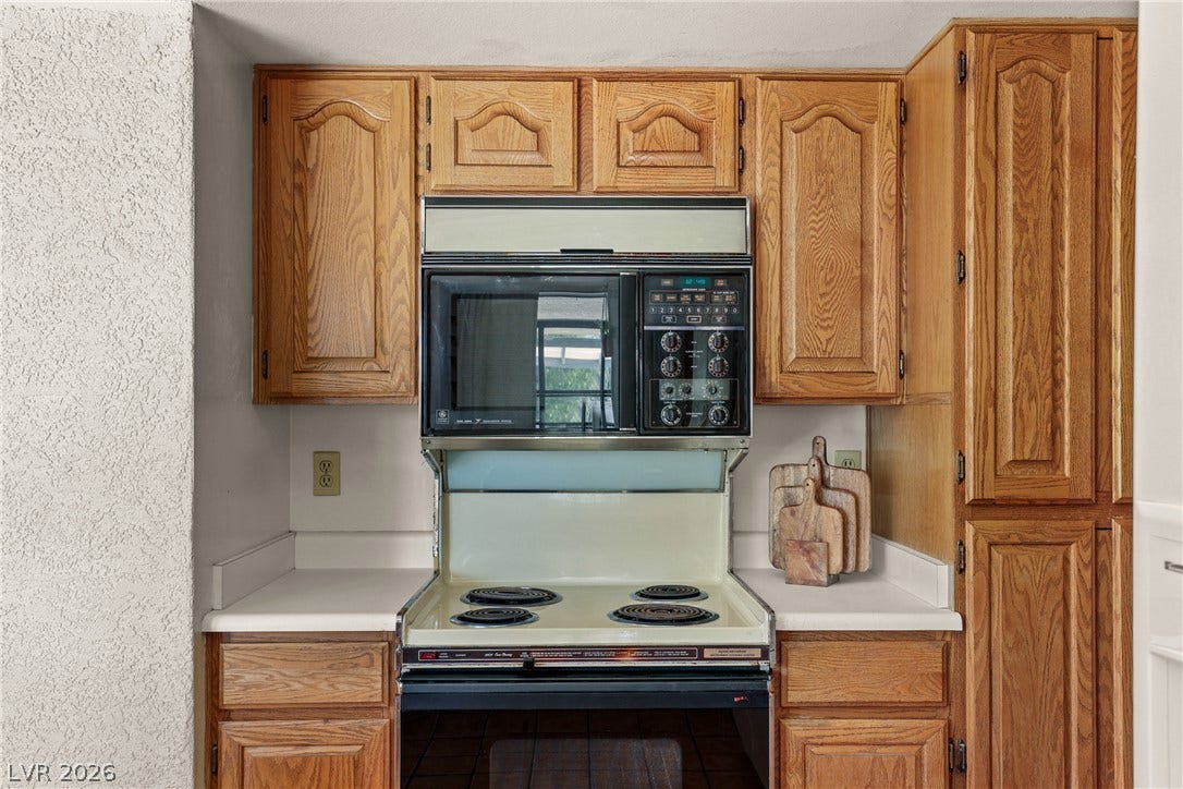 5601 Paseo Recallo Court, Las Vegas, NV 89108 Ample wooden cabinetry surrounds a vintage built-in range and overhead microwave unit.